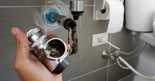 Plumber holding joints and connections of sink in a bathroom